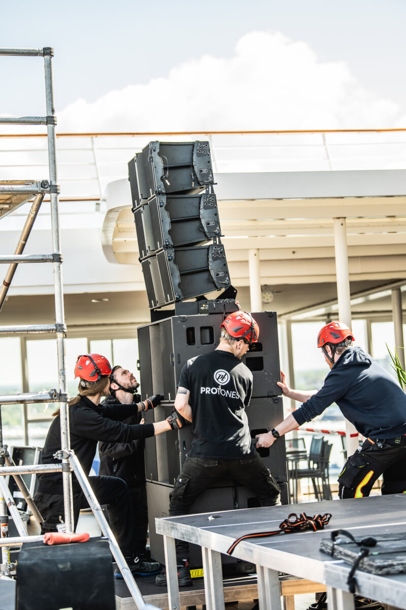 protones team packt an und installiert lautsprecher für tontechnik bei konzert auf kreuzfahrtschiff