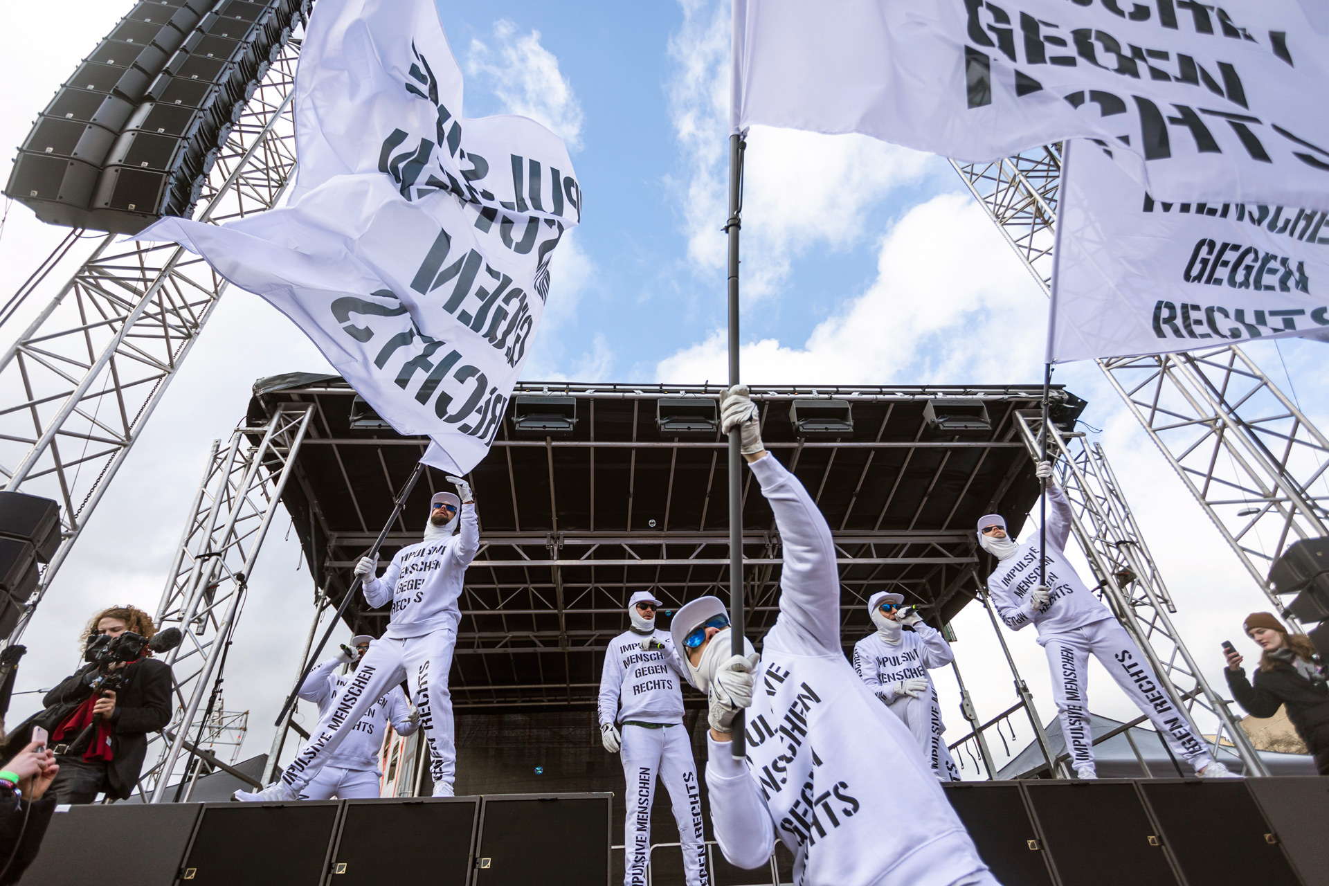 demo gegen rechts bühne mit protstierenden in weißen outfits veranstaltungstechnik für demonstrationen von protones